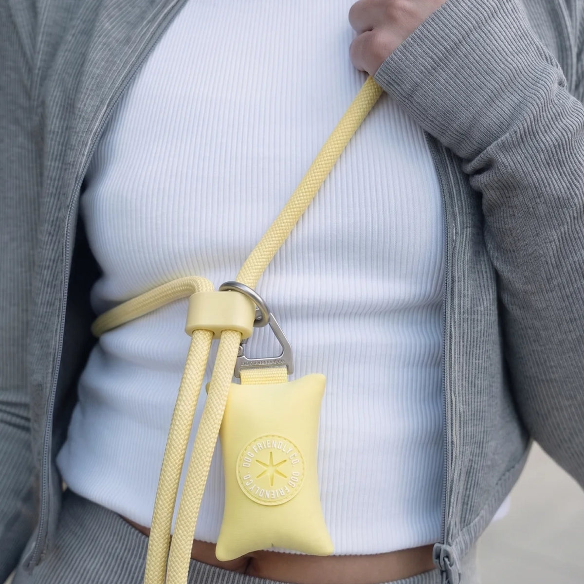 Yellow hands-free leash with a poop bag holder attached near the owner's waist.